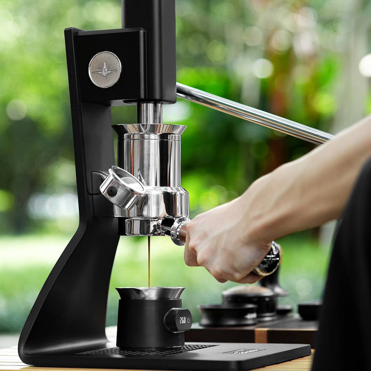 MHW-3BOMBER ES8031 black ESP coffee scale and matching cup collecting espresso beneath a manual lever machine; machine not included