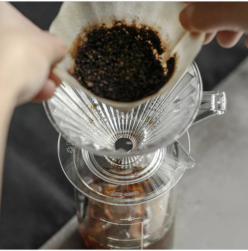 Freshly ground coffee being added to a glass pour-over dripper