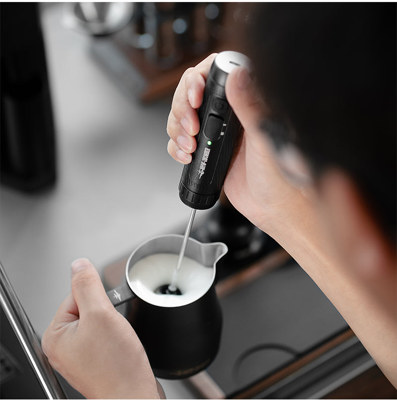 Supplier scene showing a black handheld frother working in a pitcher of milk