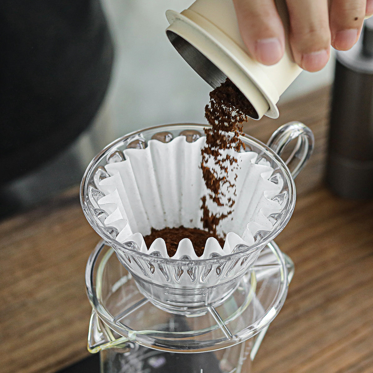Pouring ground coffee into a cake-shaped paper filter