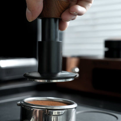 HiBREW Master 58mm Coffee Tamper — hand-held tool above a coffee basket. Demonstration props are not included.