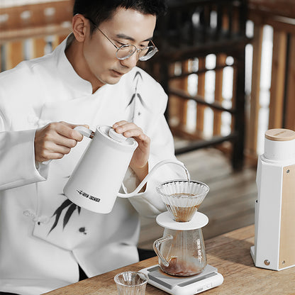 G5096 Clear server beneath a dripper while a person in a white jacket pours from a kettle. Other pictured tools, coffee and props are not included.