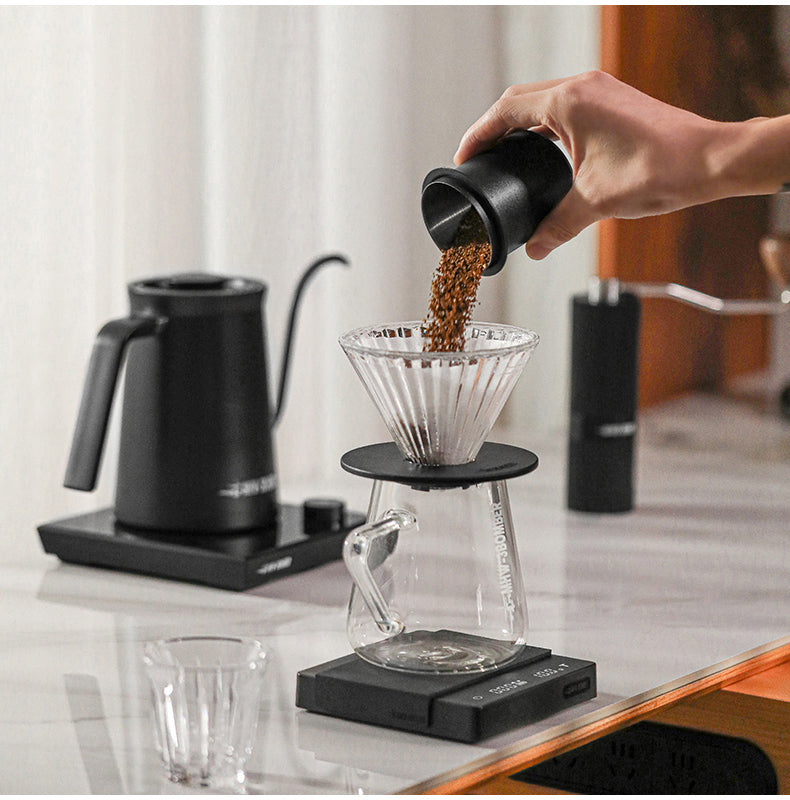 MHW-3BOMBER DC5615B matte black dosing cup pouring grounds into a pour-over dripper; dripper, server, scale and kettle are separate props