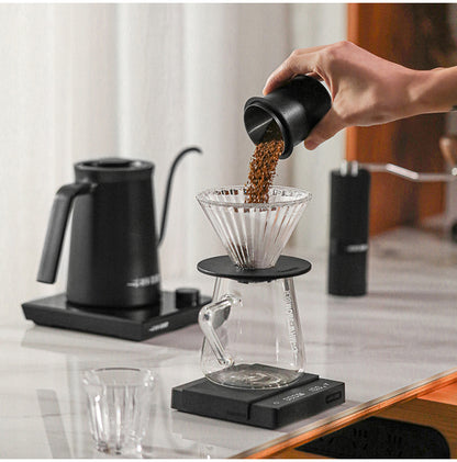 MHW-3BOMBER DC5615B matte black dosing cup pouring grounds into a pour-over dripper; dripper, server, scale and kettle are separate props