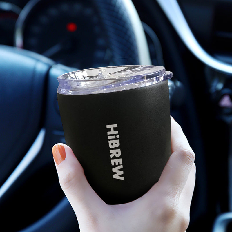Black HiBREW portable coffee mug held in a hand
