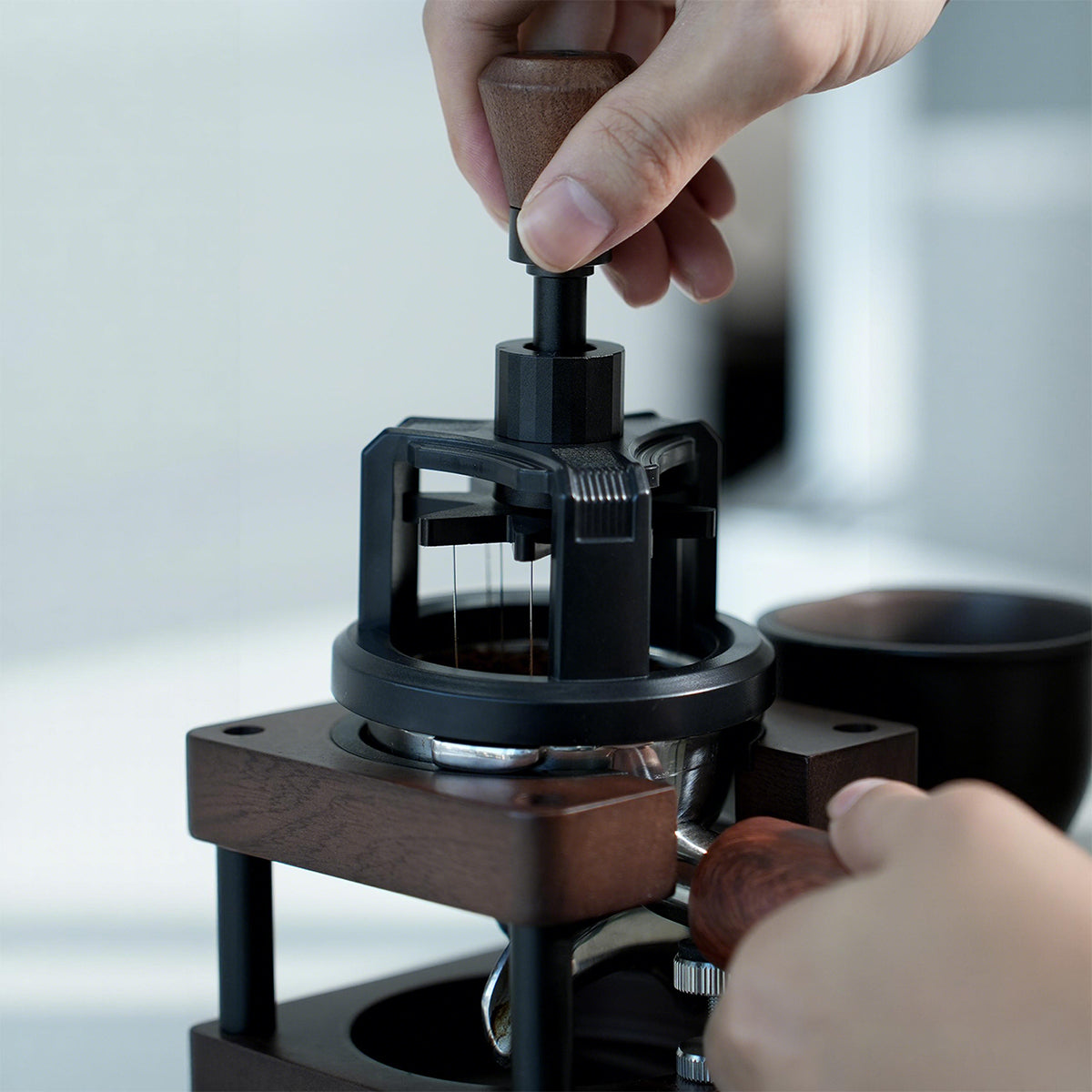 HiBREW Rotary 58mm WDT Tool — hand operating the rotary handle above a basket. Demonstration props are not included.