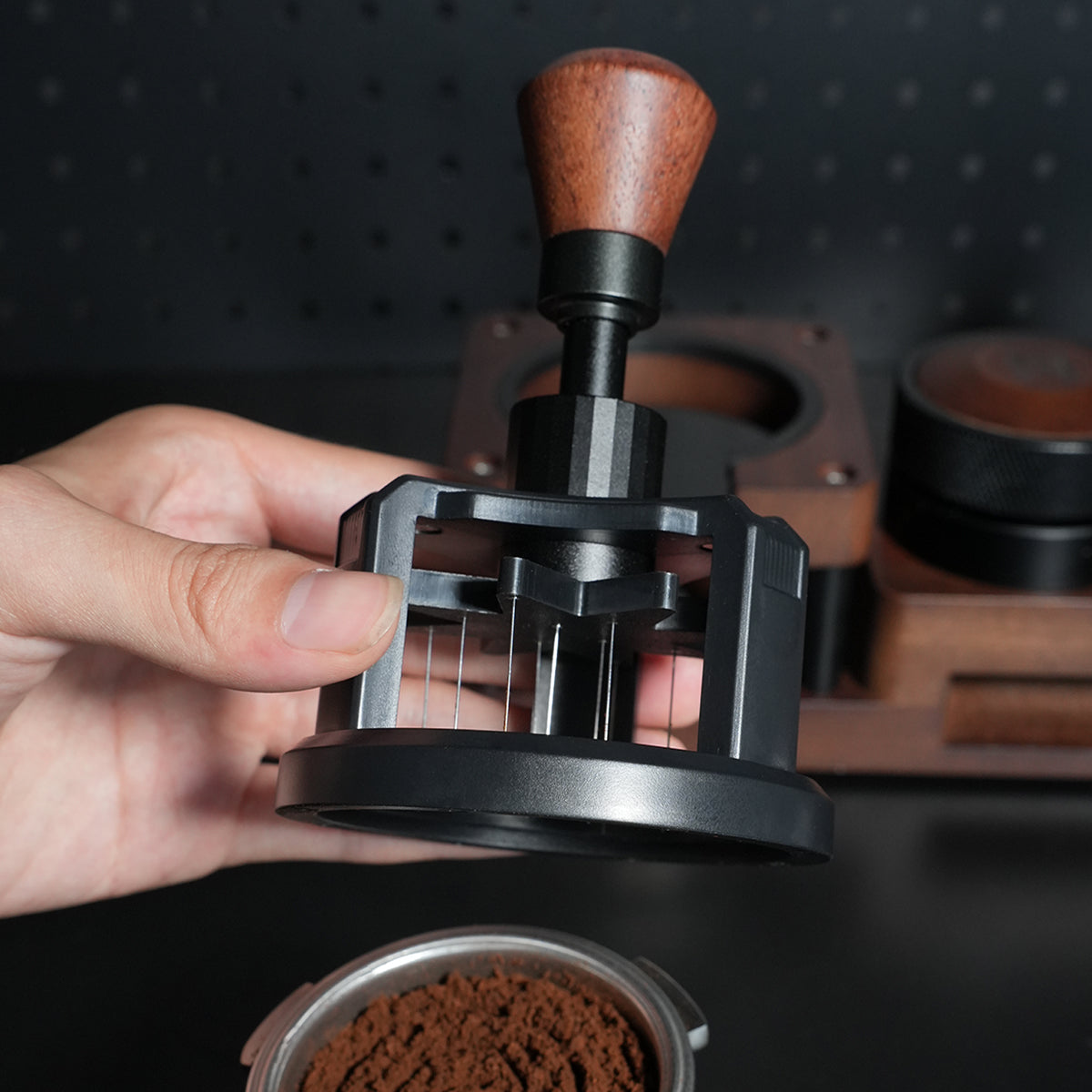HiBREW Rotary 58mm WDT Tool — needle assembly shown by hand above a portafilter. Demonstration props are not included.