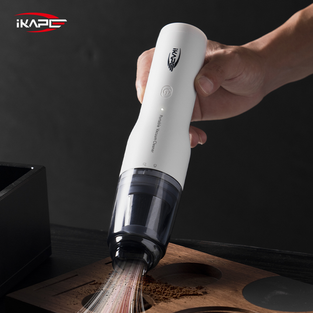IKAPE White handheld vacuum with a brush attachment cleaning coffee grounds