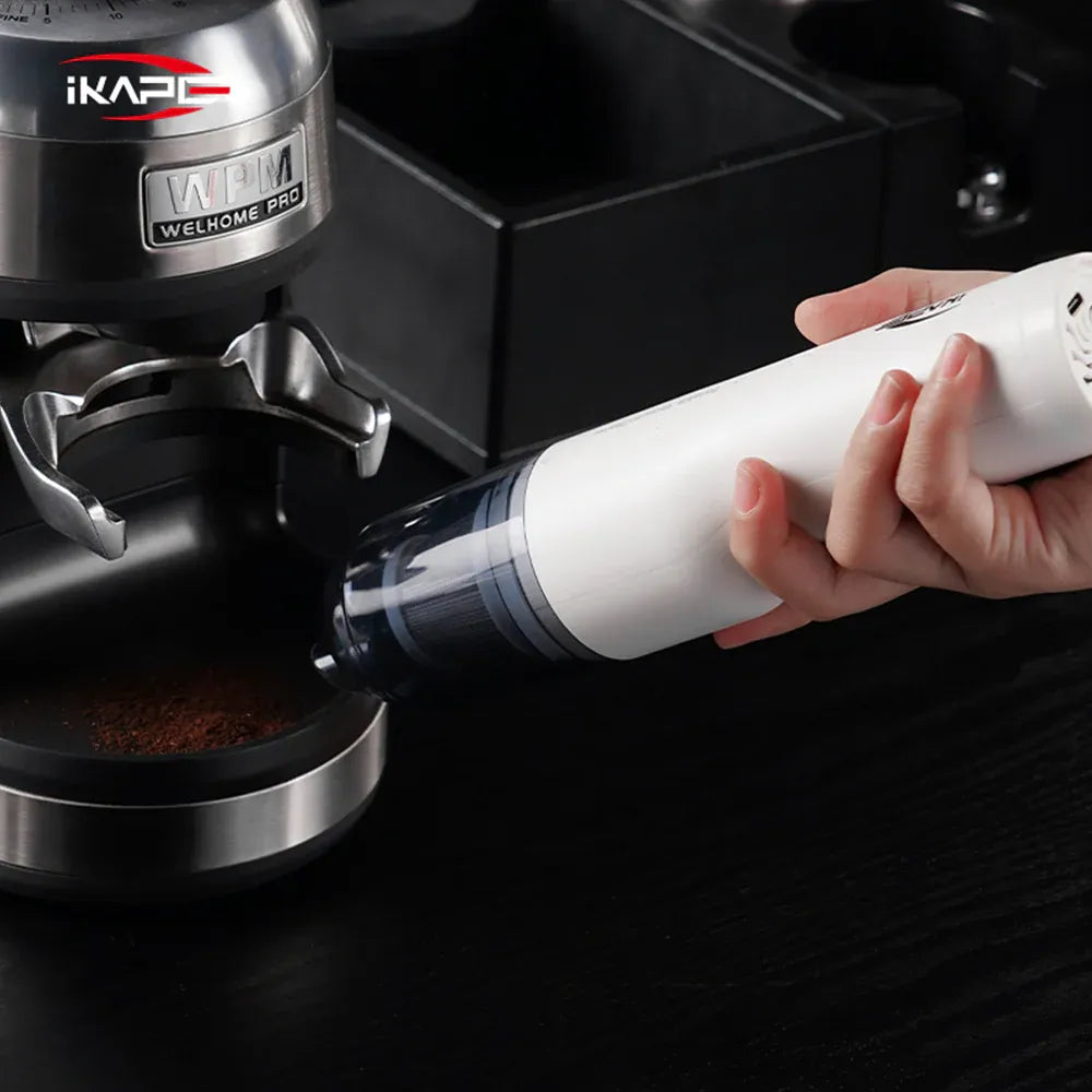 IKAPE White handheld vacuum cleaning dry coffee grounds around an espresso machine