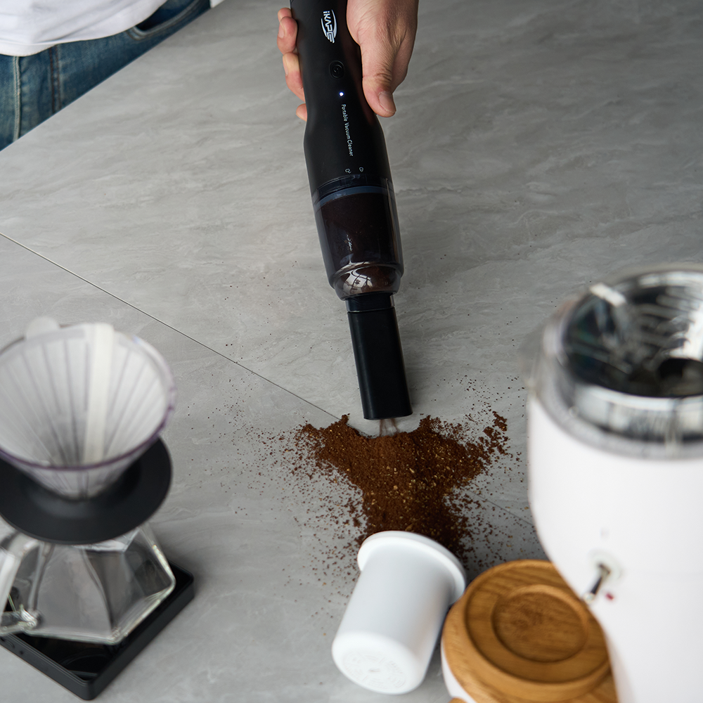 IKAPE Black handheld coffee-ground vacuum cleaning a countertop
