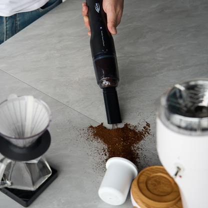 IKAPE Black handheld coffee-ground vacuum cleaning a countertop