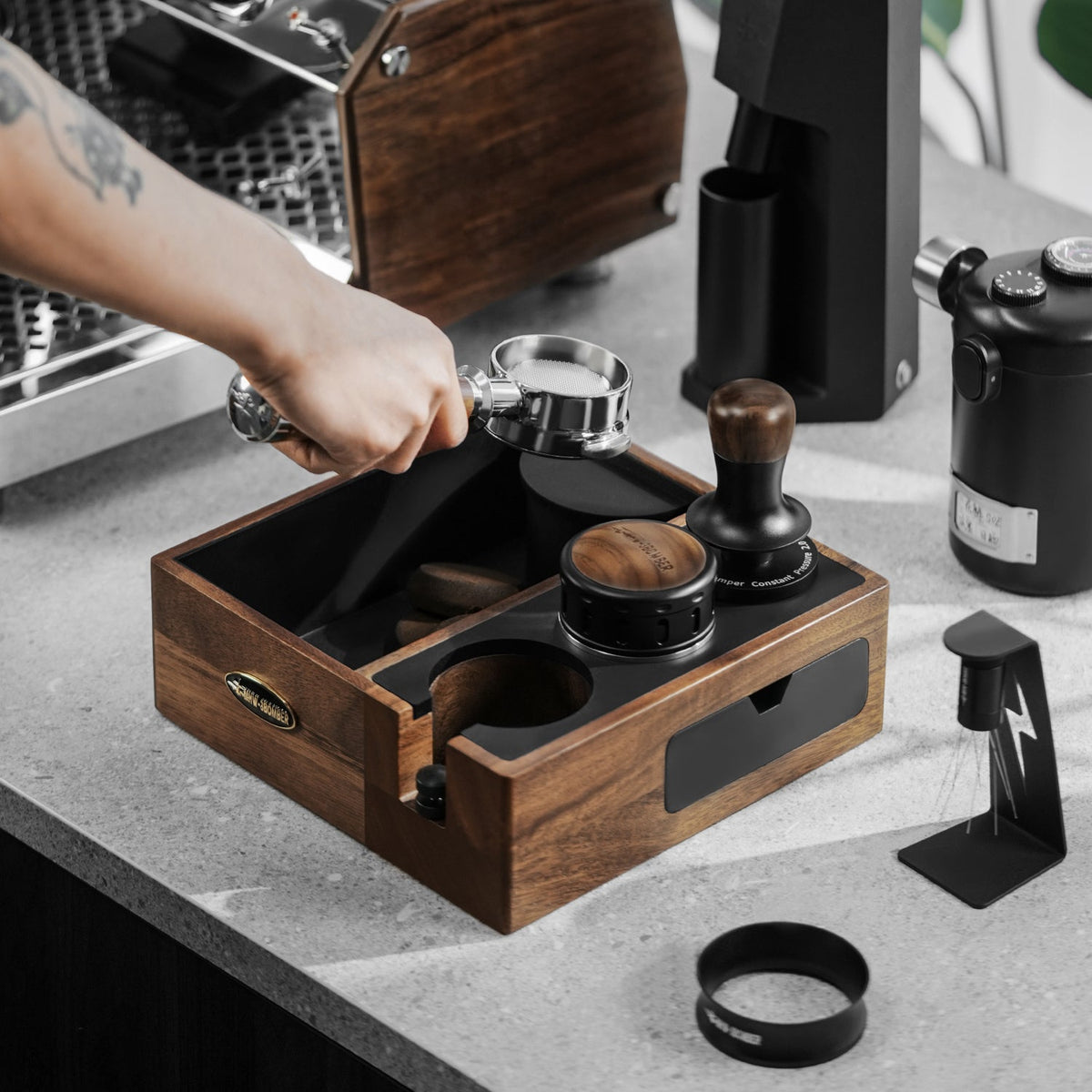 MHW-3BOMBER Walnut CH6624 multifunction knock box in use for coffee-puck disposal; coffee tools and machine are props