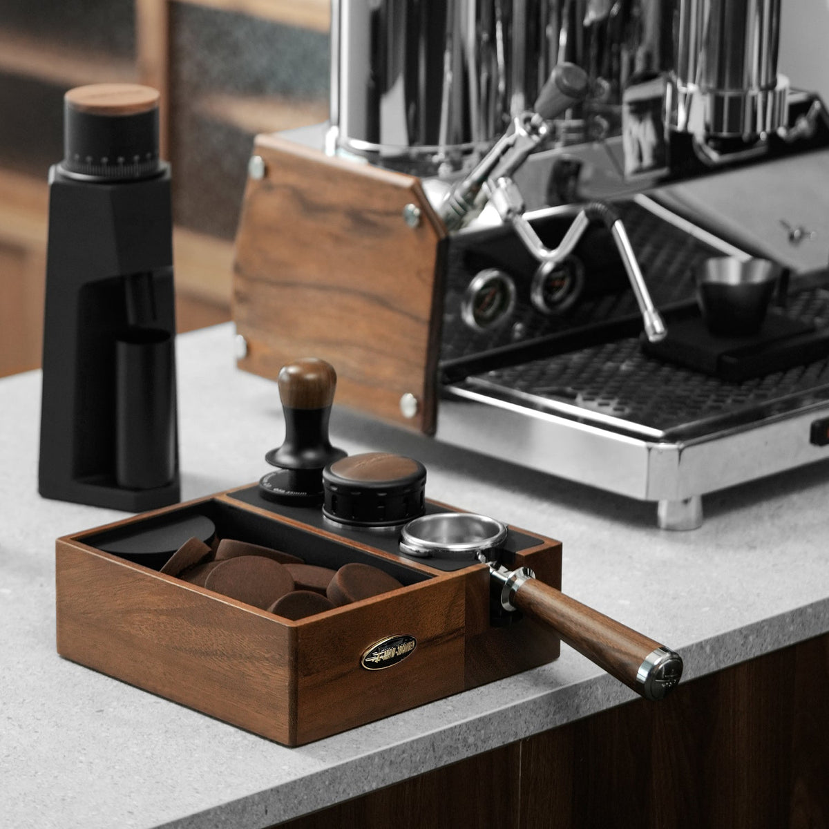 MHW-3BOMBER Walnut CH6624 multifunction knock box beside an espresso machine; tools and machine are props
