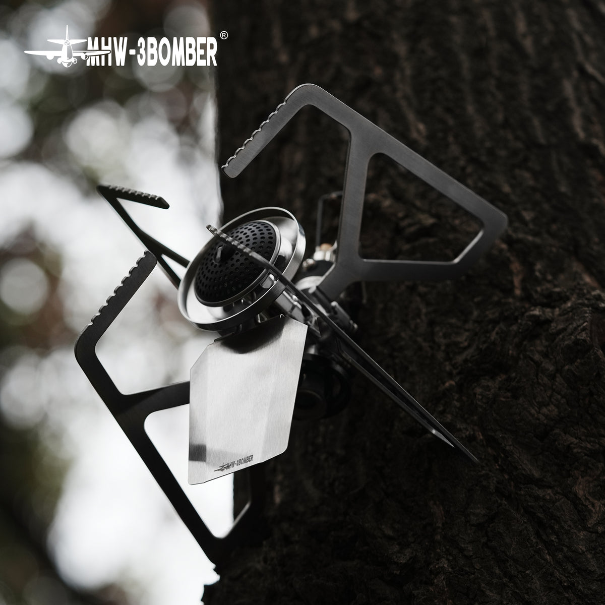 MHW-3BOMBER MET stove unfolded on a tree surface, burner and supports visible