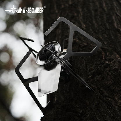 MHW-3BOMBER MET stove unfolded on a tree surface, burner and supports visible