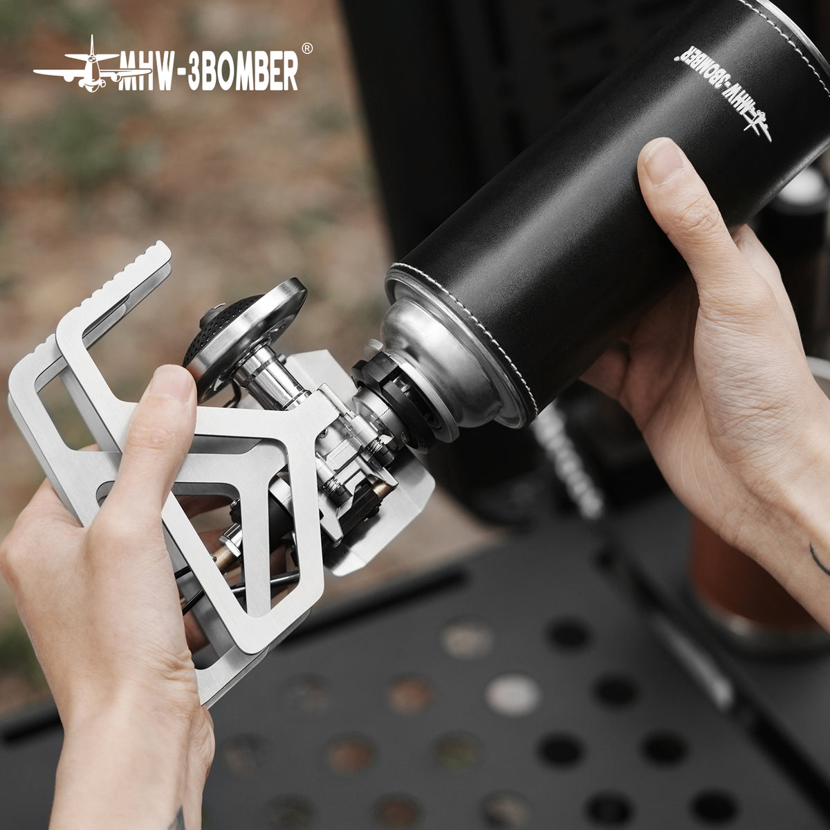 MHW-3BOMBER MET stove held during a folded-form connection demonstration; separate cylinder is a reference prop and is not included