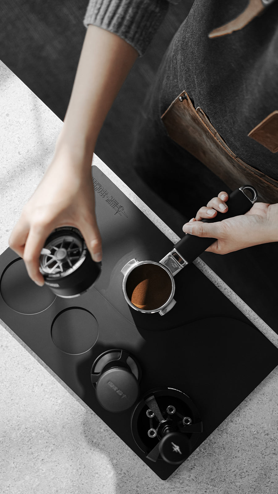 MHW-3BOMBER Black recessed Yu mat during portafilter preparation at a workstation; tools not included