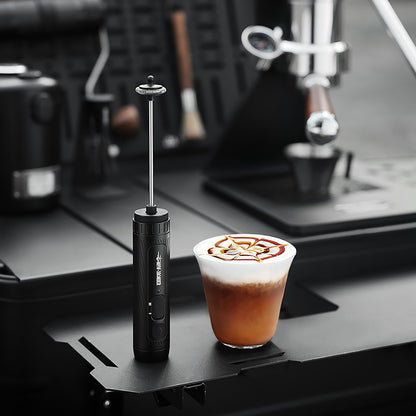 MHW-3BOMBER MF5893 black handheld milk frother beside a prepared coffee