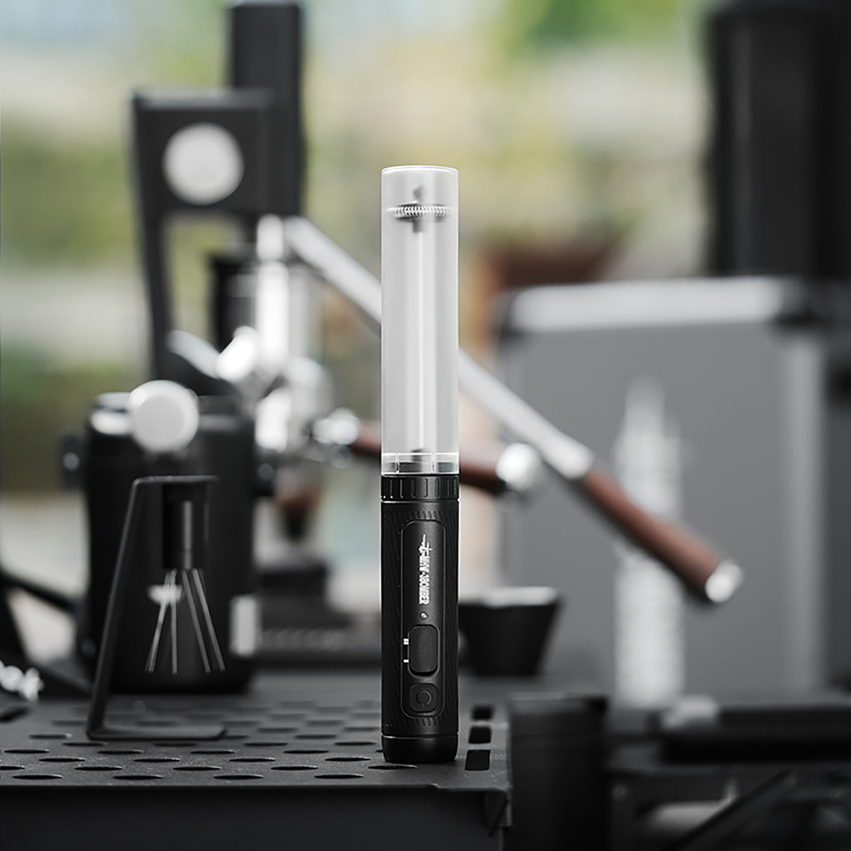 MHW-3BOMBER MF5893 black handheld milk frother shown in a coffee workspace