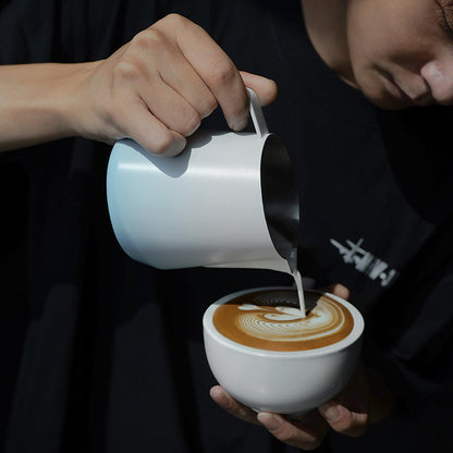 MHW-3BOMBER P6847BL GT milk pitcher — 600 ml gradient blue, latte pour, dark-shirt barista. Cups, milk and scene props are not included.