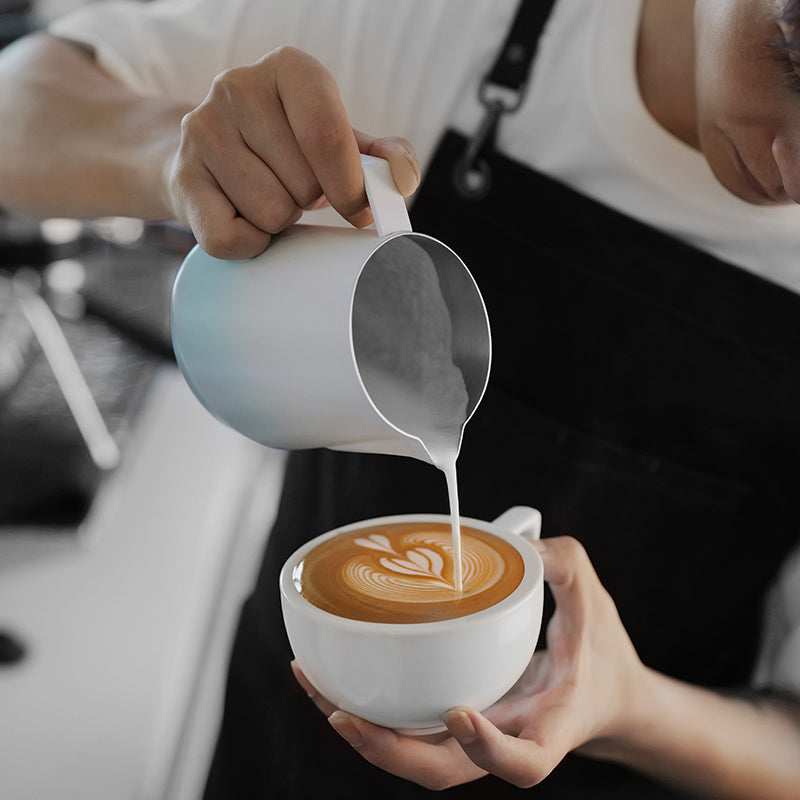 MHW-3BOMBER P6847BL GT milk pitcher — 600 ml gradient blue, latte pour, light-shirt barista. Cups, milk and scene props are not included.