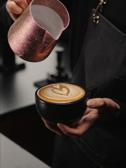 MHW-3BOMBER P6635R Spark 600 ml Titanium Milk Pitcher pouring latte art into a black cup; cup is not included