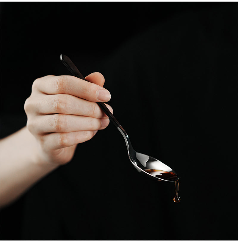 MHW-3BOMBER black and silver cupping spoon held by hand