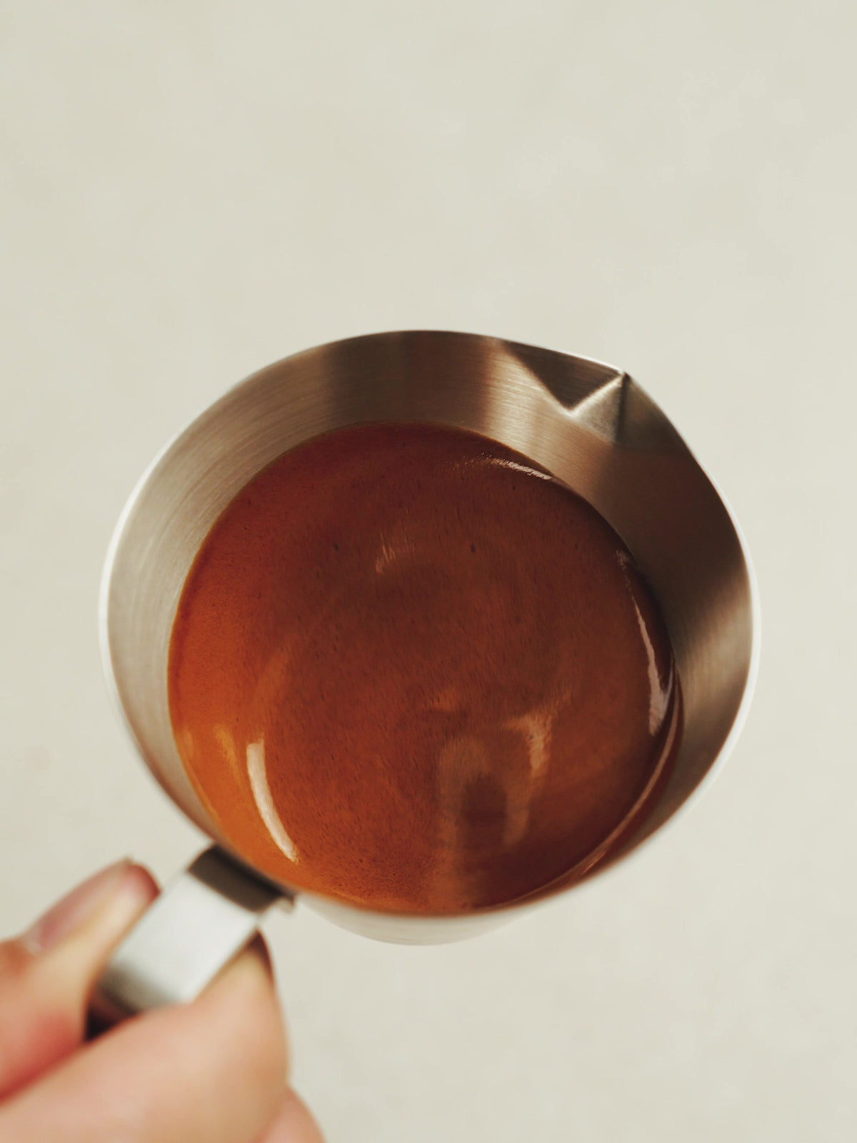 MHW-3BOMBER G5140 satin single-spout measuring cup with espresso, held by its handle