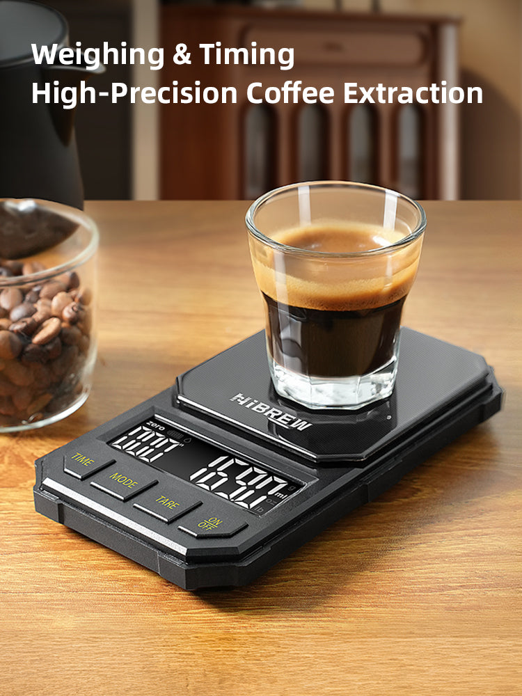HiBREW black 1000g coffee scale — Black four-button 1000g scale with espresso cup on a wooden worktop; cup excluded.