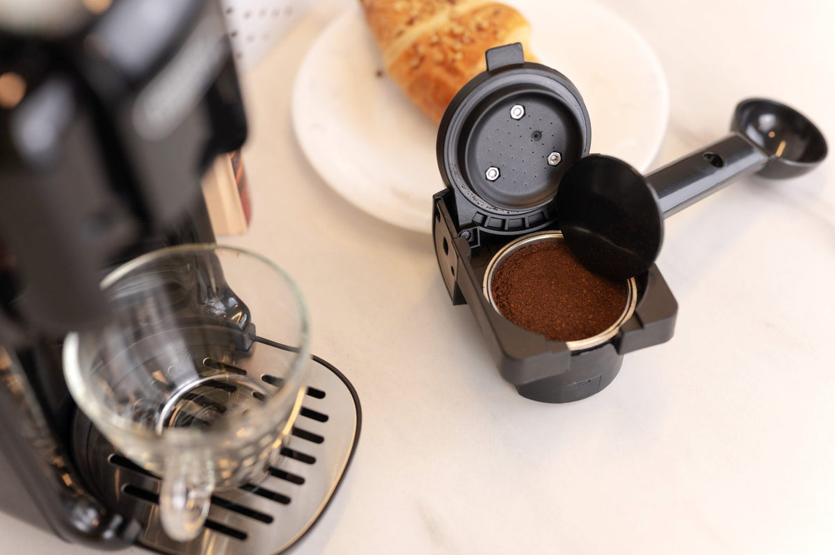 HiBREW H2B ground-coffee adapter beside the Black machine during preparation; cup and coffee are scene props