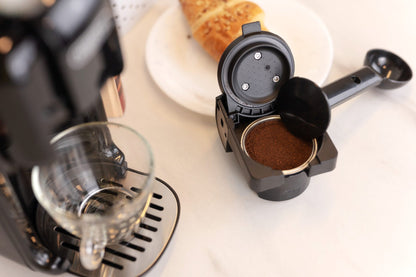 HiBREW H2B ground-coffee adapter beside the Black machine during preparation; cup and coffee are scene props