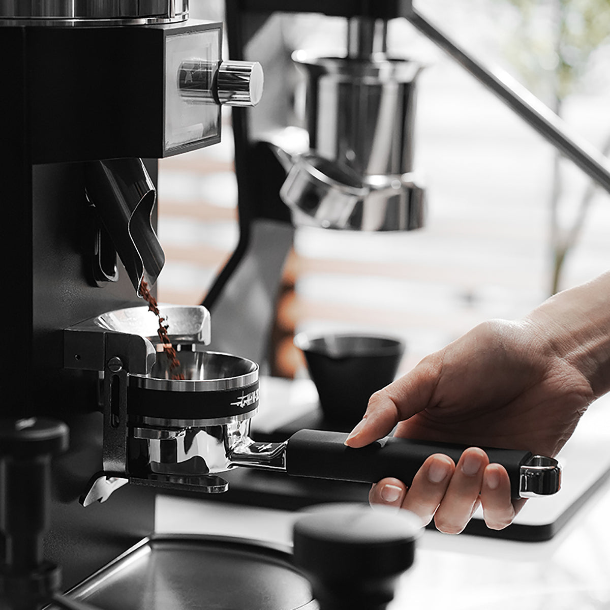 MHW-3BOMBER T5879 Yu one-piece bottomless portafilter receiving coffee grounds, side view; grinder and dosing ring not included