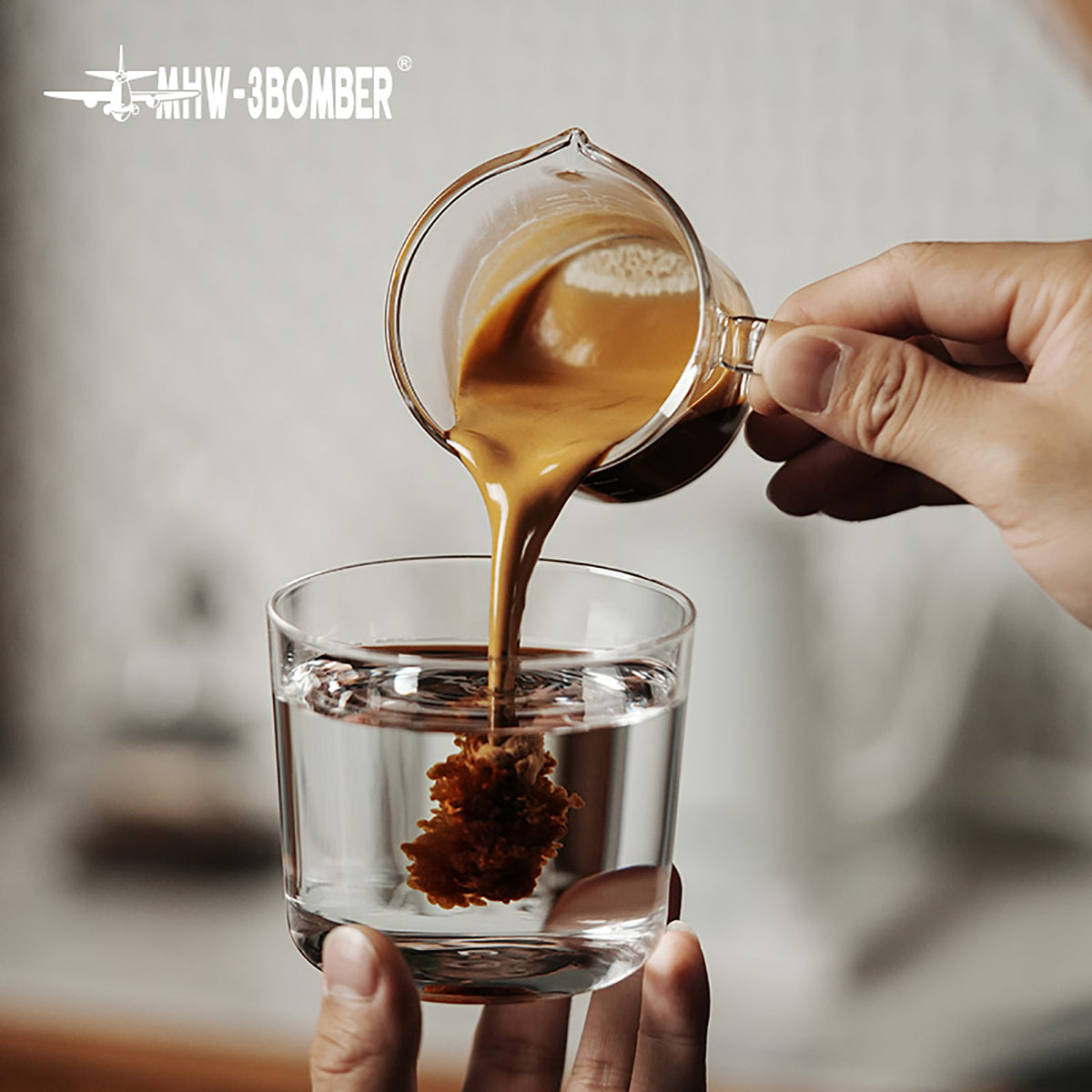 MHW-3BOMBER G5059 clear glass measuring cup pouring espresso into a held glass