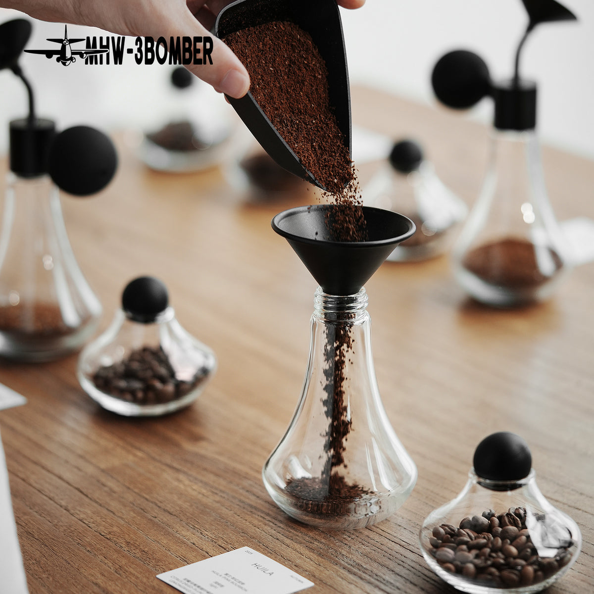 Filling the detached glass body of the AB5677 Coffee Aroma Bottle with coffee grounds; other table items are props