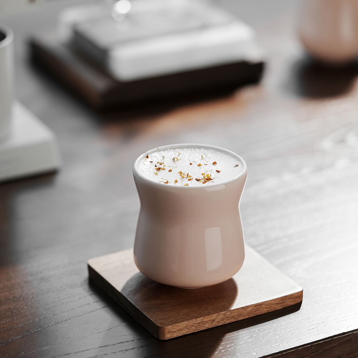 Lotus pink wide-rim Aura cup on a wooden coaster with a prepared drink. Coaster and drink are presentation props.