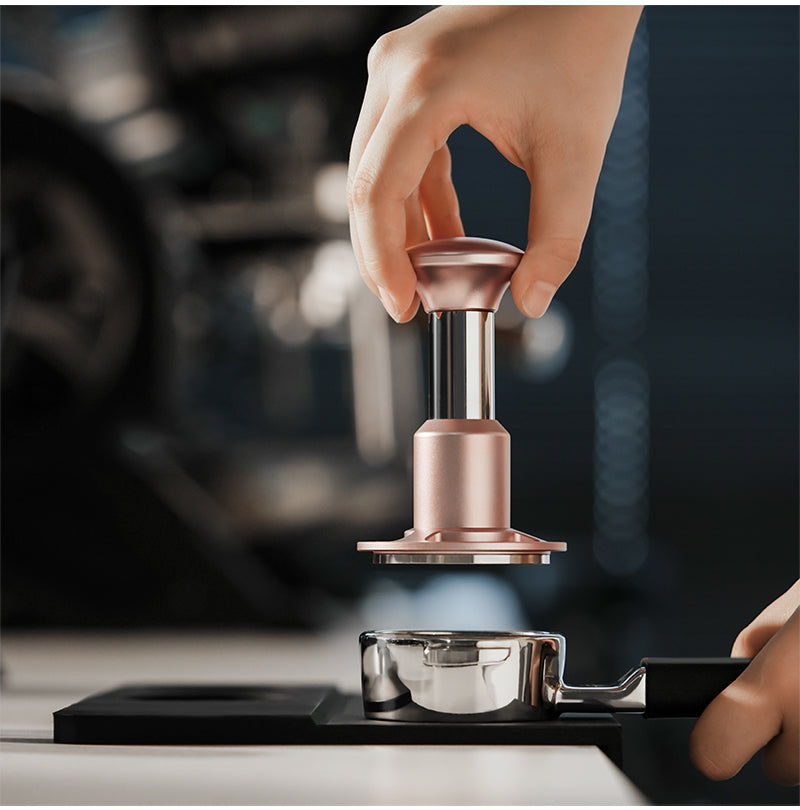 Pink 58.35 mm Knight Impact Tamper held above a basket; portafilter and station are photo props