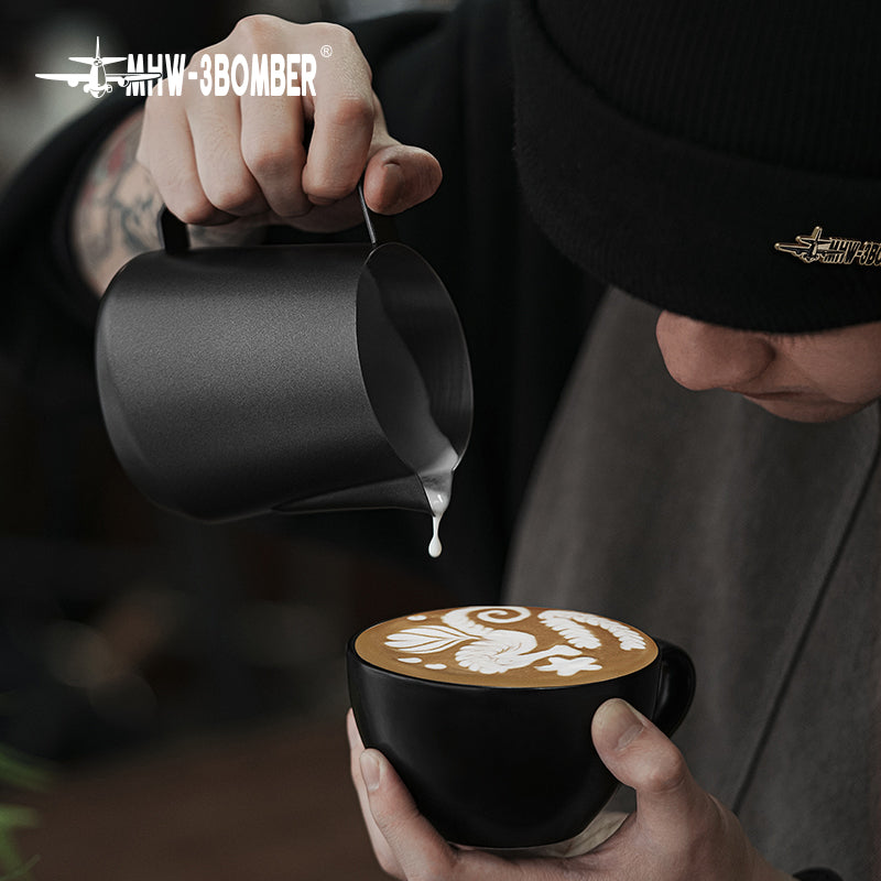 MHW-3BOMBER P5184 GT milk pitcher — 600 ml matte black, low-angle latte pour. Cups, machines and scene items are not included.
