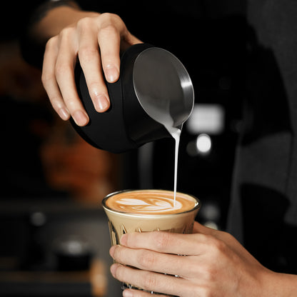 P6513B black GT handleless 400 ml milk pitcher — pouring into a glass cup. Cups and other scene items are not included.