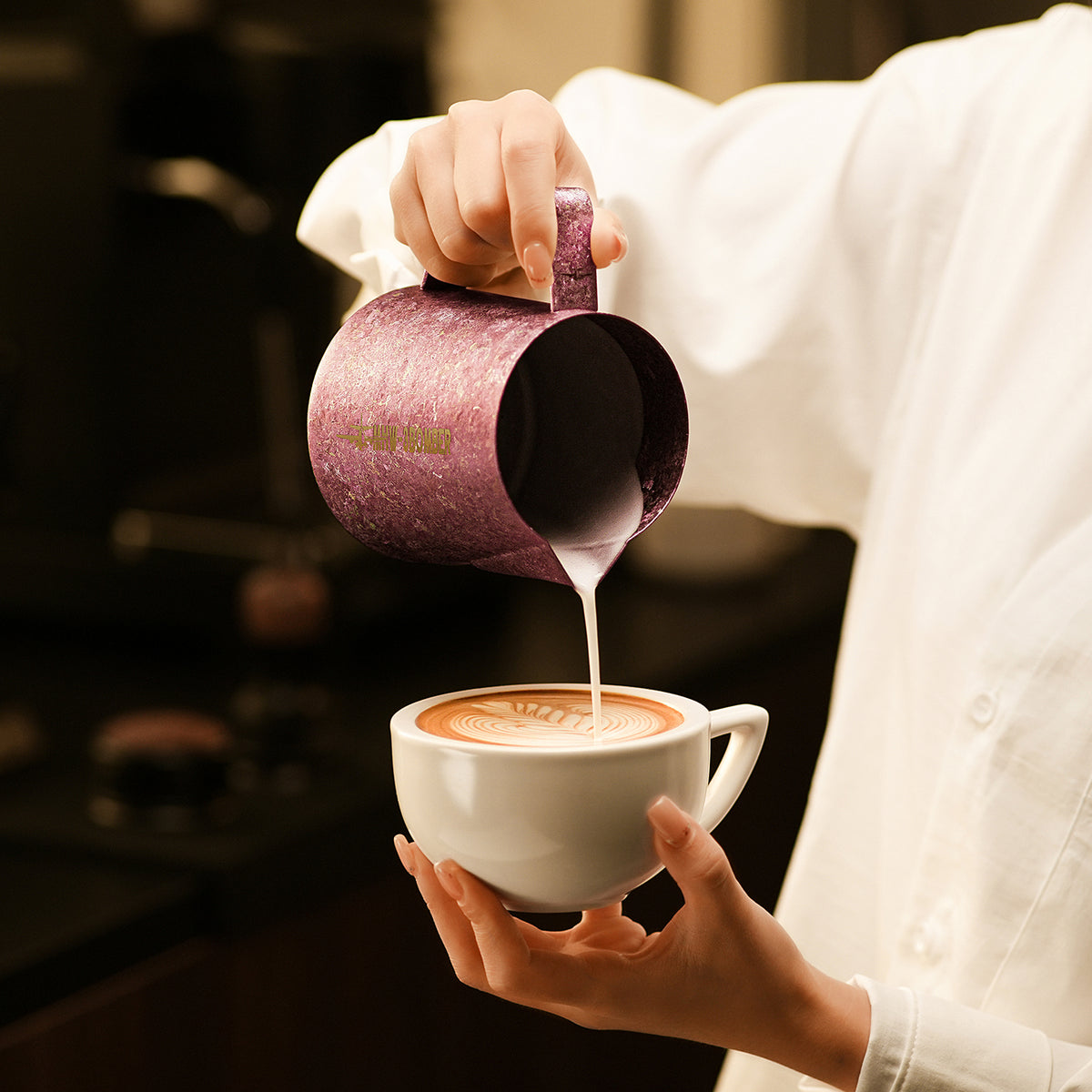 P6635R Spark Titanium series 600 ml milk pitcher — pouring into a white cup. Cups and scene items are not included.