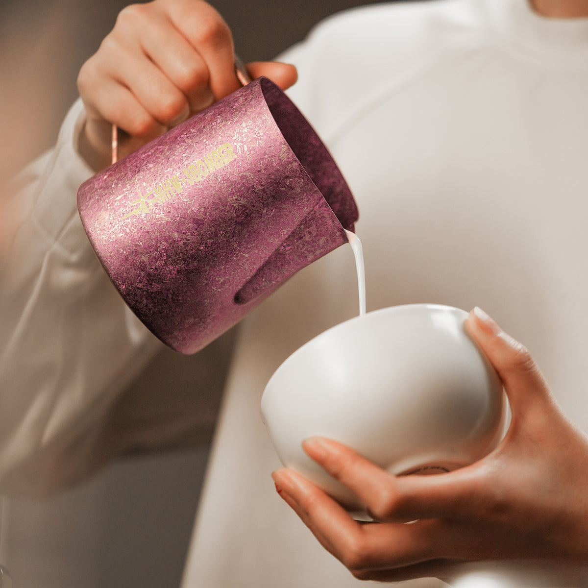 P6635R Spark Titanium series 600 ml milk pitcher — close-up pouring into a white cup. Cups and scene items are not included.