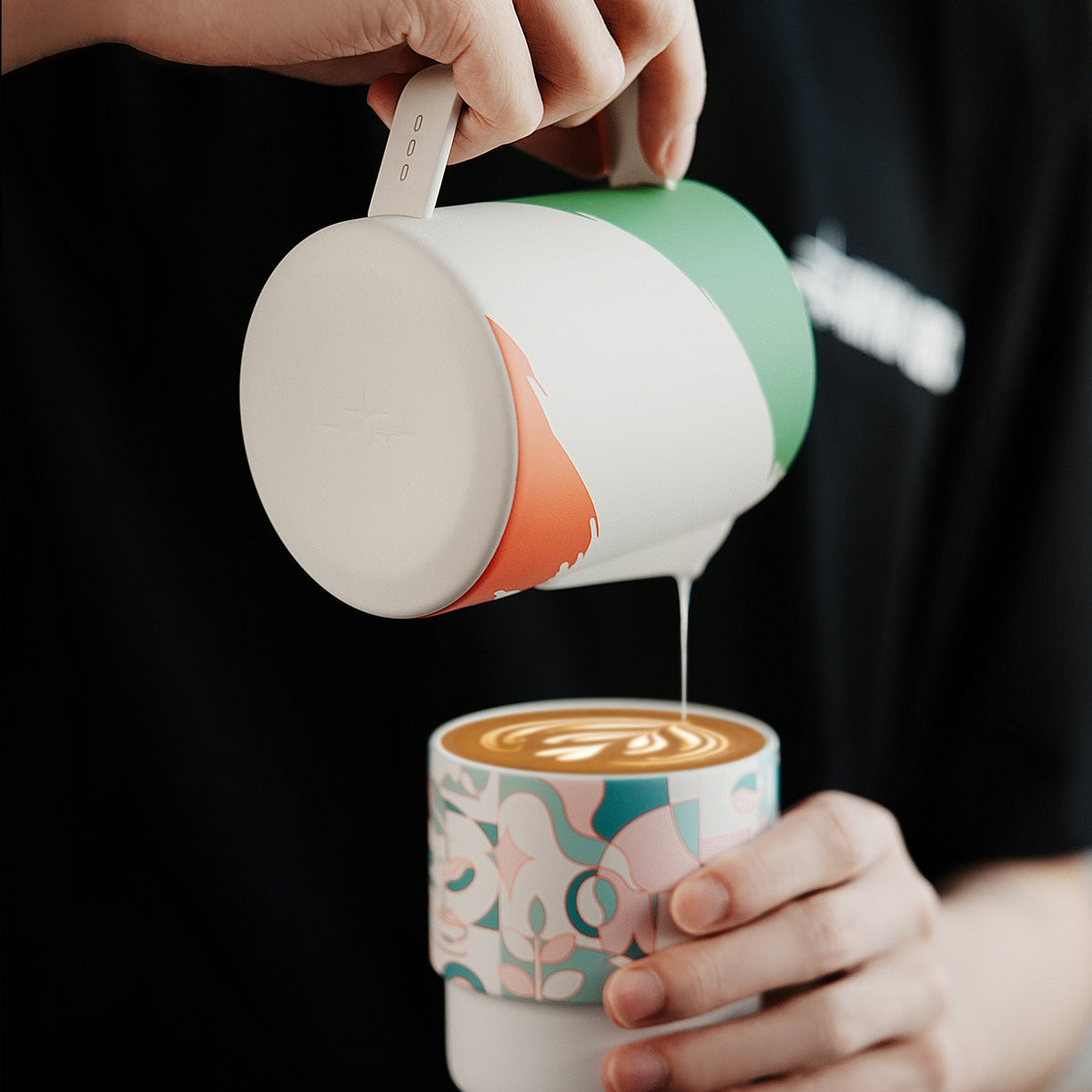 MHW-3BOMBER P6941 Milk Pitcher 5.0, 500 ml WBC Milan artwork — latte pour into a patterned cup. Tamper, cups and other scene items are not included.