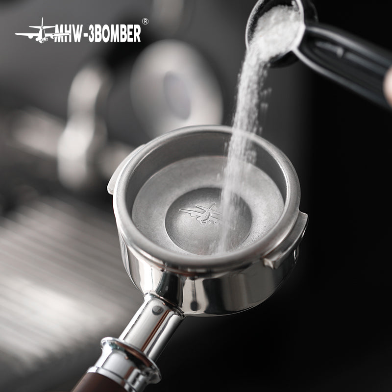 MHW-3BOMBER BB5497 blind bowl in a portafilter being rinsed from a kettle; kettle and portafilter are scene props