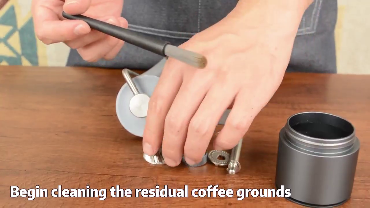 Brushing the disassembled burr components of the CERA+ CG01 manual coffee grinder