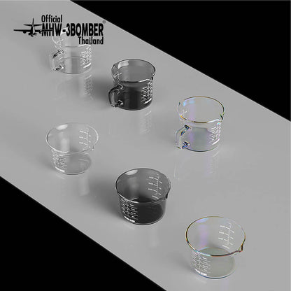 MHW-3BOMBER measuring-cup comparison: clear G5052 single-spout at front left and clear G5059 handled double-spout at back left; configurations sold separately