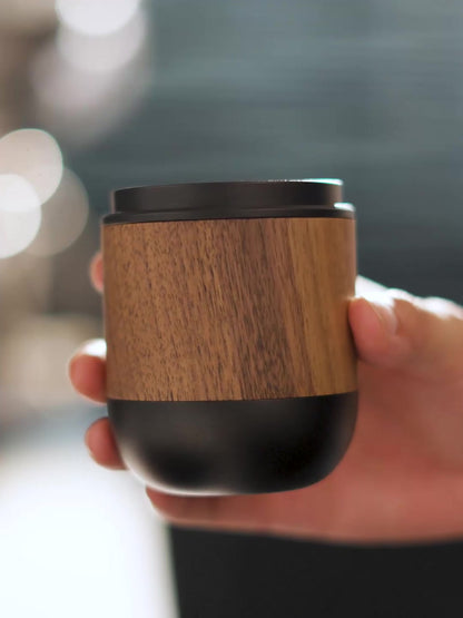 MHW-3BOMBER DR6543B Nova 58 mm black dosing cup held by hand, showing the walnut grip and black rim and base