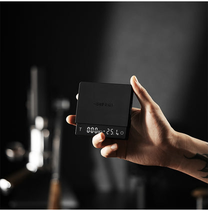 Black ES5788B Cube Coffee Scale 3.0 Micro held in one hand, showing its platform and front display
