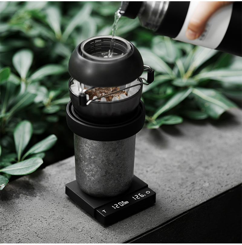 Black ES5788B Cube Coffee Scale 3.0 Micro under a pour-over brewer in an outdoor scene; brewer and kettle are props