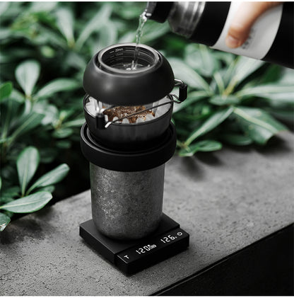 Black ES5788B Cube Coffee Scale 3.0 Micro under a pour-over brewer in an outdoor scene; brewer and kettle are props