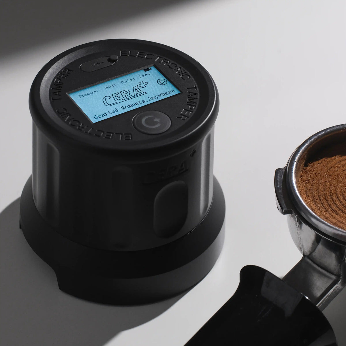 CERA+ ET58 black electronic tamper beside a prepared espresso puck; portafilter excluded