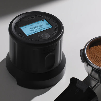 CERA+ ET58 black electronic tamper beside a prepared espresso puck; portafilter excluded